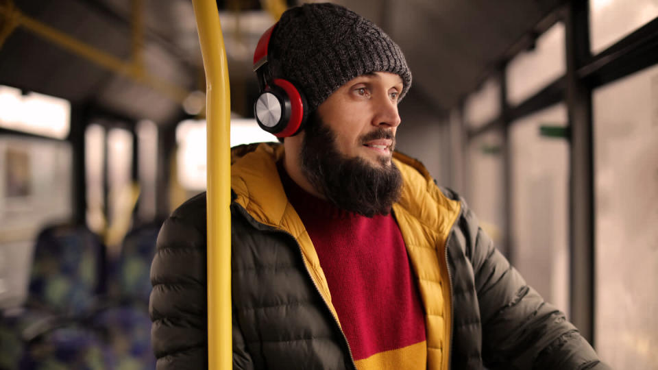 Mature man with headphones listening to music on public transport