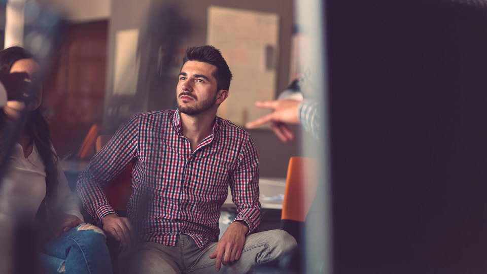 Man in checked shirt listening to colleagues