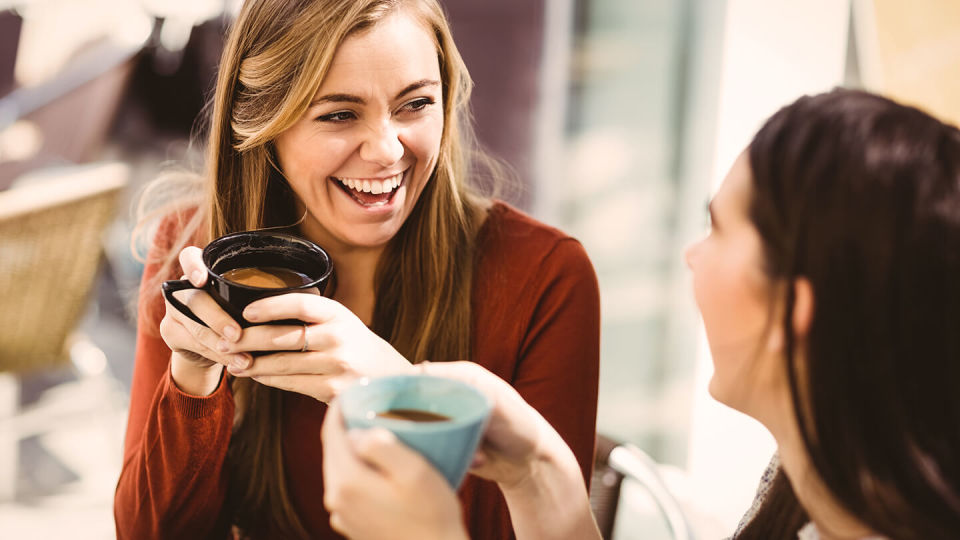 Young women smiling over coffee