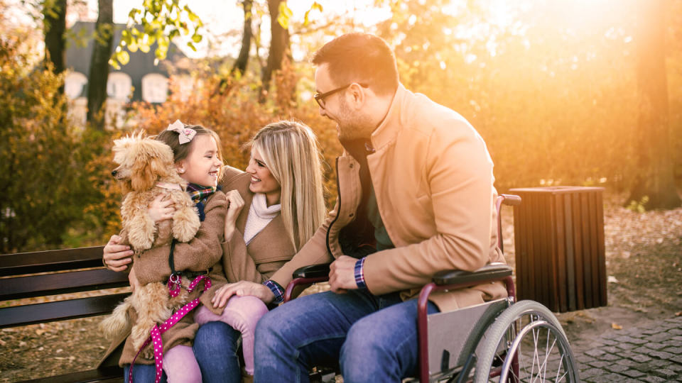 Disabled father in wheelchair with his daughter, wife and dog in the park