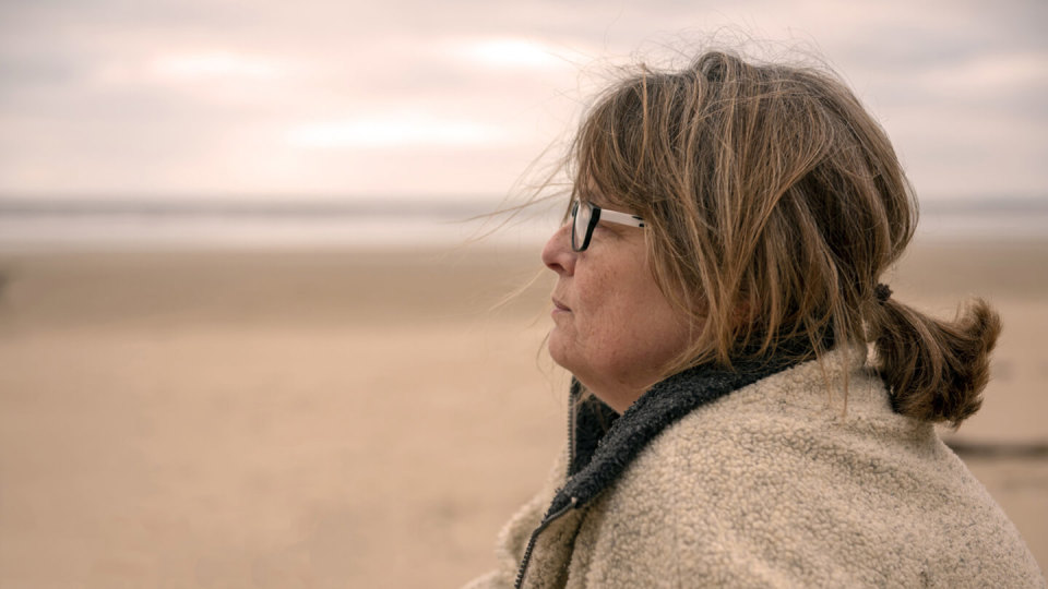 Close-up of mature woman stood on the beach